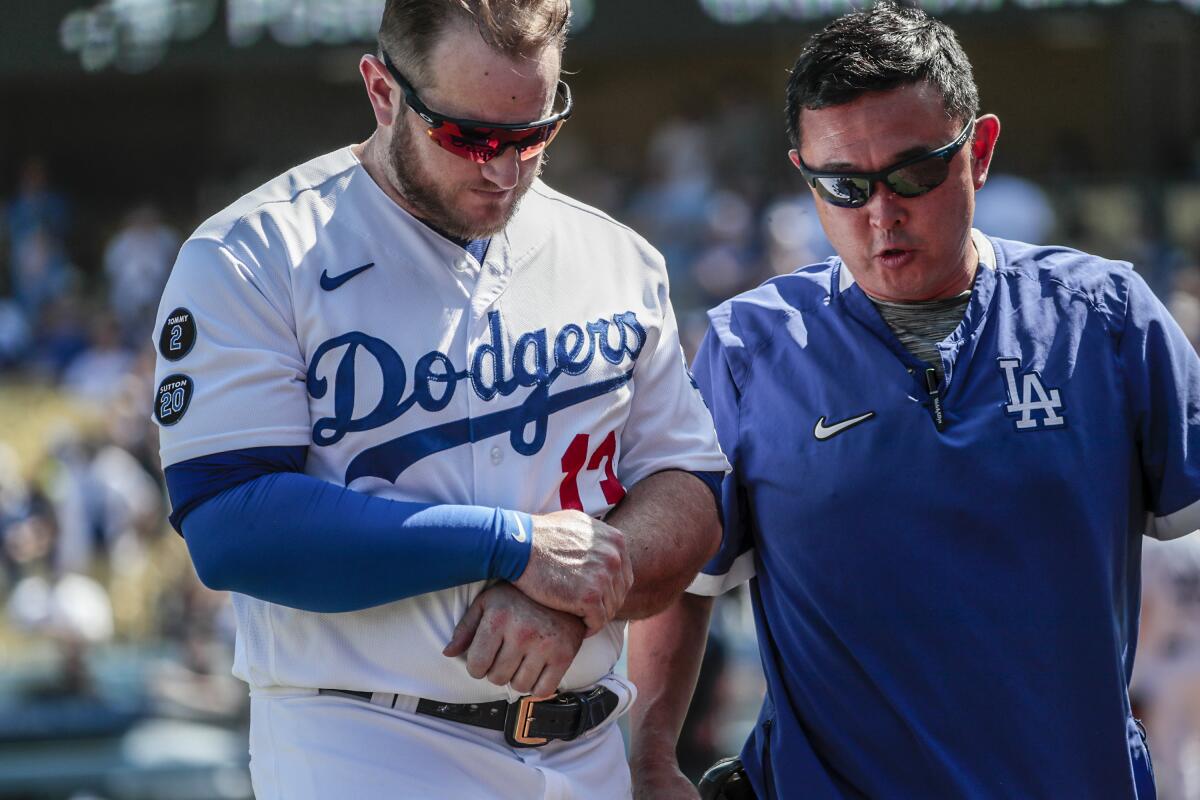 Dodgers first baseman Max Muncy leaves the field with team trainer Neil Rampe.