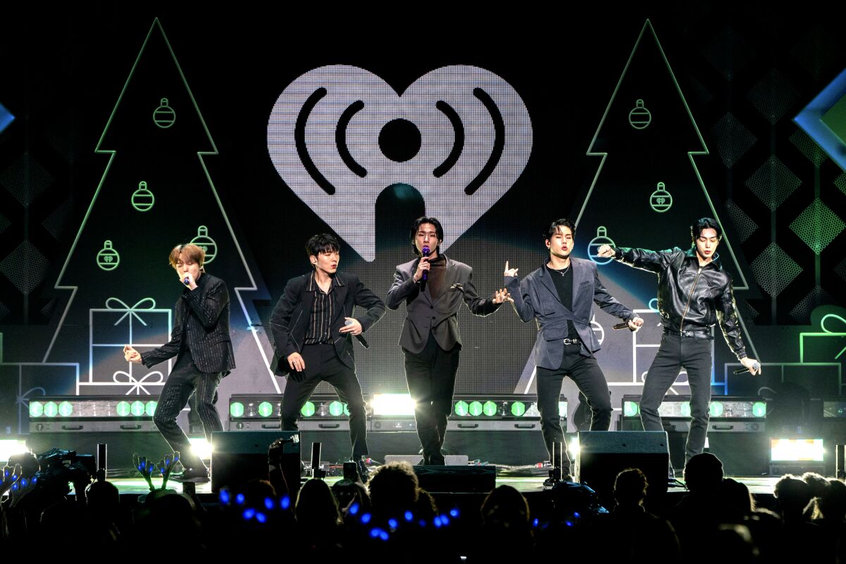 A five-member K-pop boy band performs onstage.