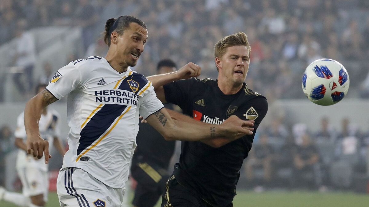 LAFC defender Walker Zimmerman, right, battles Galaxy forward Zlatan Ibrahimovic for control of the ball in the first half at the Banc of California Stadium on July 26.