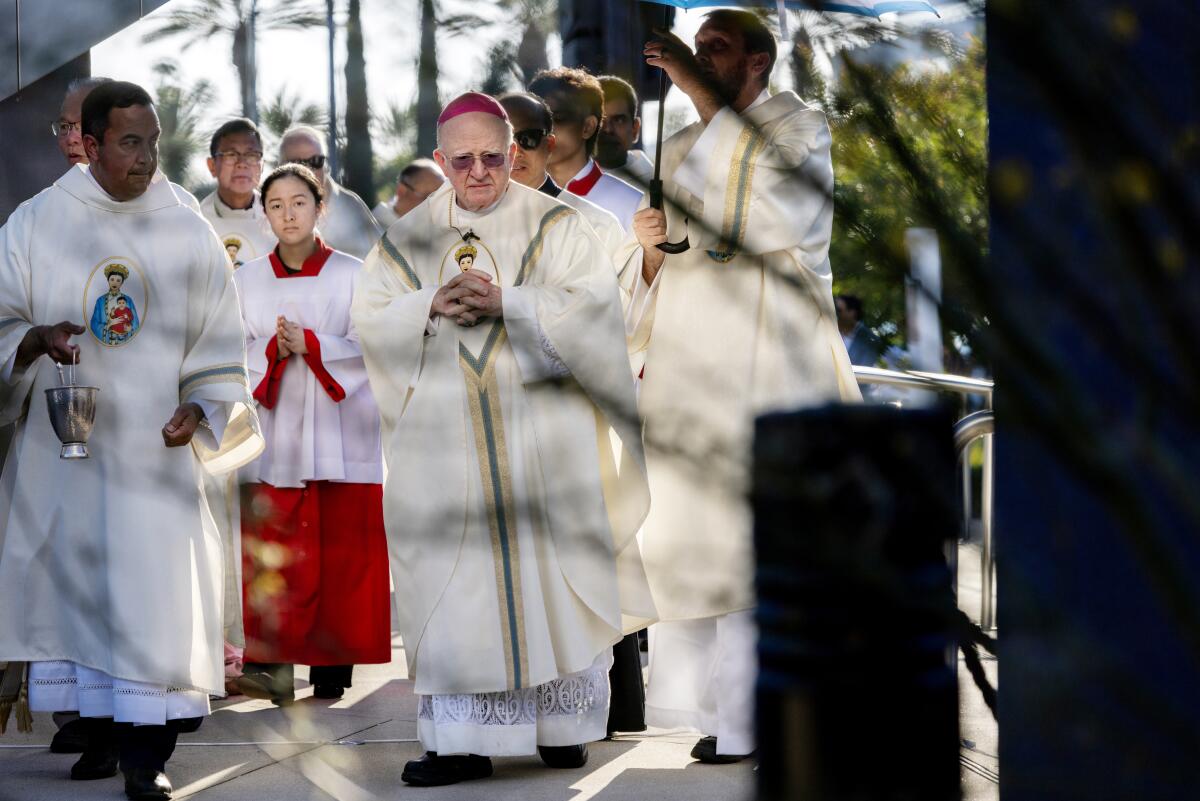 Bishop Kevin Vann, center, walks with fingers laced together among fellow congregants at Christ Cathedral