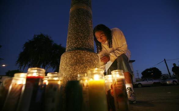 Family friend Helen Boyd lights candles on 114th Street near Central Avenue in Watts to mark the one-year anniversary of the fatal shooting of 15-year-old Dovon Harris while he was on his way home from school.