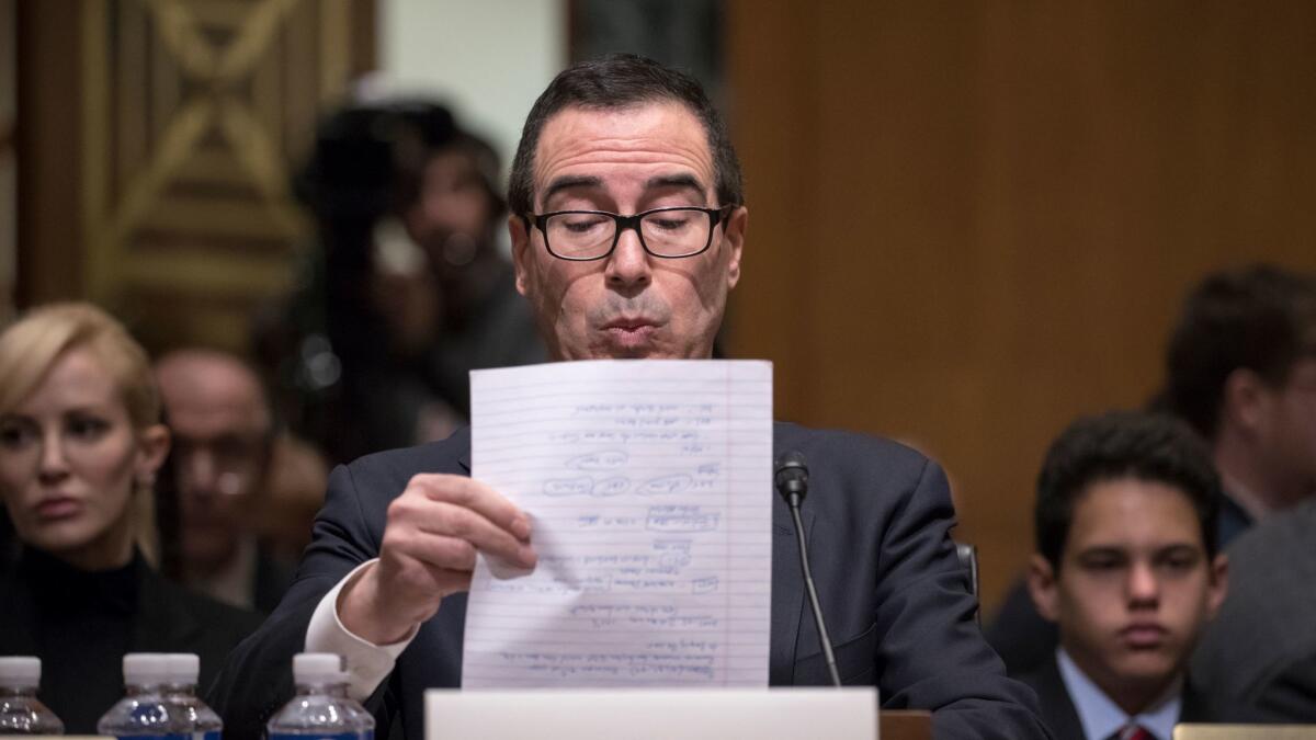 Treasury Secretary-designate Steven Mnuchin goes over notes during his confirmation hearing in January. His then-fiancee, Louise Linton, who now may be more famous than he is, can be seen at far left.
