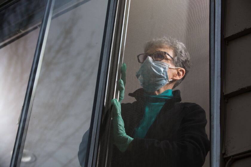 Pat McCauley, stares out the window of her home in Kirkland, Wash. where she can see the red flashing lights of the medics that come and go from the Life Care Center on March 10, 2020. She and her husband decided to quarantine themselves in their home after a good friend of theirs, a Life Care resident, died on Sunday of COVID-19. They are mourning him, and anxiously waiting for the results of their own COVID-19 tests. (photo by Karen Ducey)