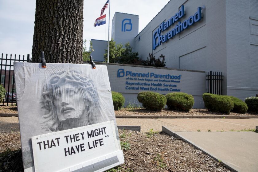 An abortion opponent's sign rests against a tree outside a Planned Parenthood clinic in St. Louis on Tuesday, June 4, 2019. A legal fight between the Planned Parenthood clinic, the last abortion clinic in the state, and the state of Missouri's health department continues. (Whitney Curtis for Los Angeles Times)