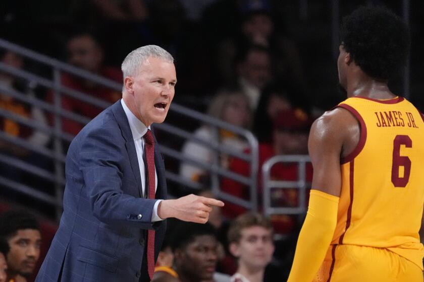 Southern California head coach Andy Enfield, left, talks with guard Bronny James during the first half of an NCAA college basketball game against Utah Thursday, Feb. 15, 2024, in Los Angeles. (AP Photo/Mark J. Terrill)
