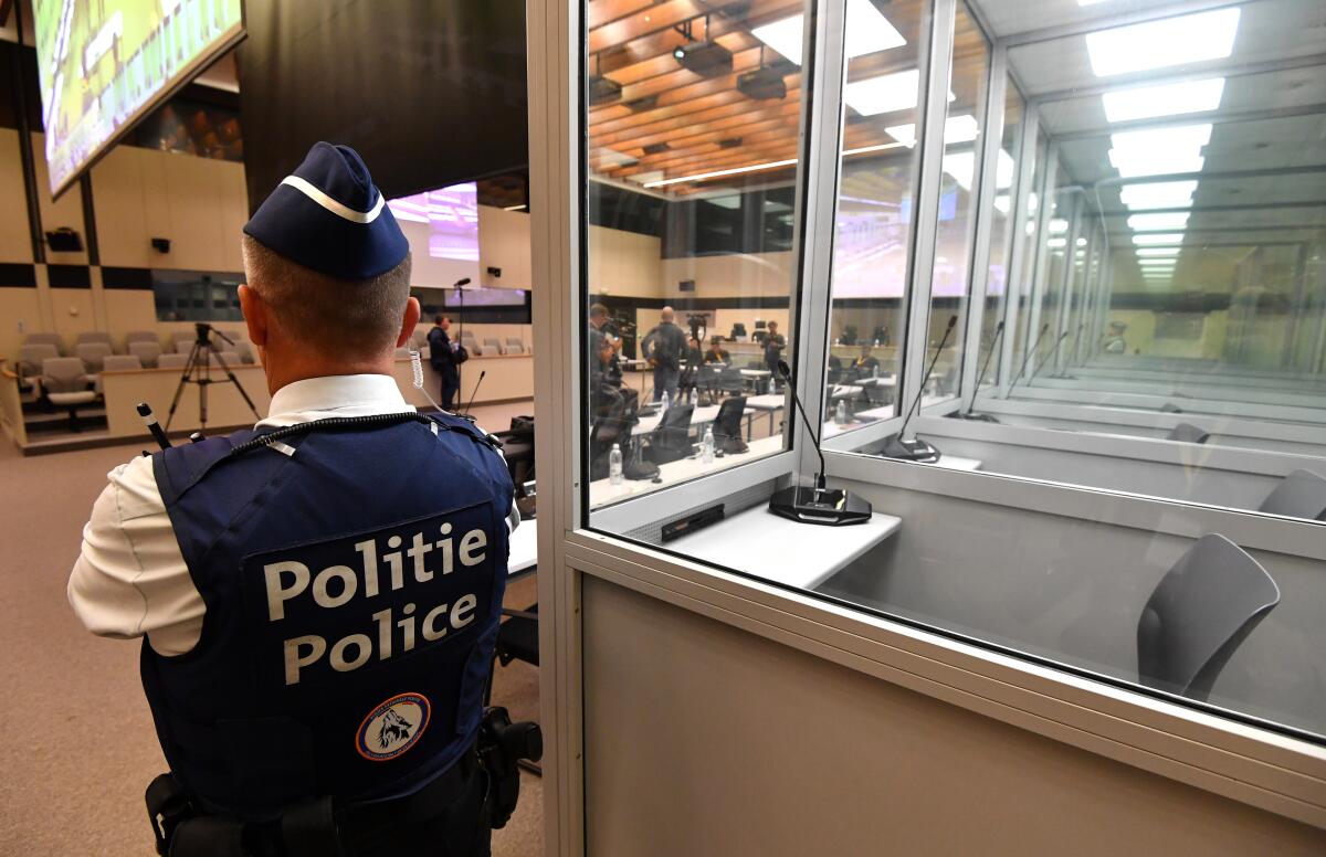 A police officer stands next to glass boxes for the defendants in the courtroom prior to the preliminary hearing, for the Brussels attacks that took place on March 22, 2016, at the Justitia building in Brussels, Monday, Sept. 12, 2022. The preliminary hearing for the terrorist attacks on Brussels airport and Maelbeek metro station which took place on March 22, 2016 will open with a preliminary hearing with the full trial beginning in October 2022. (John Thys, Pool Photo via AP)