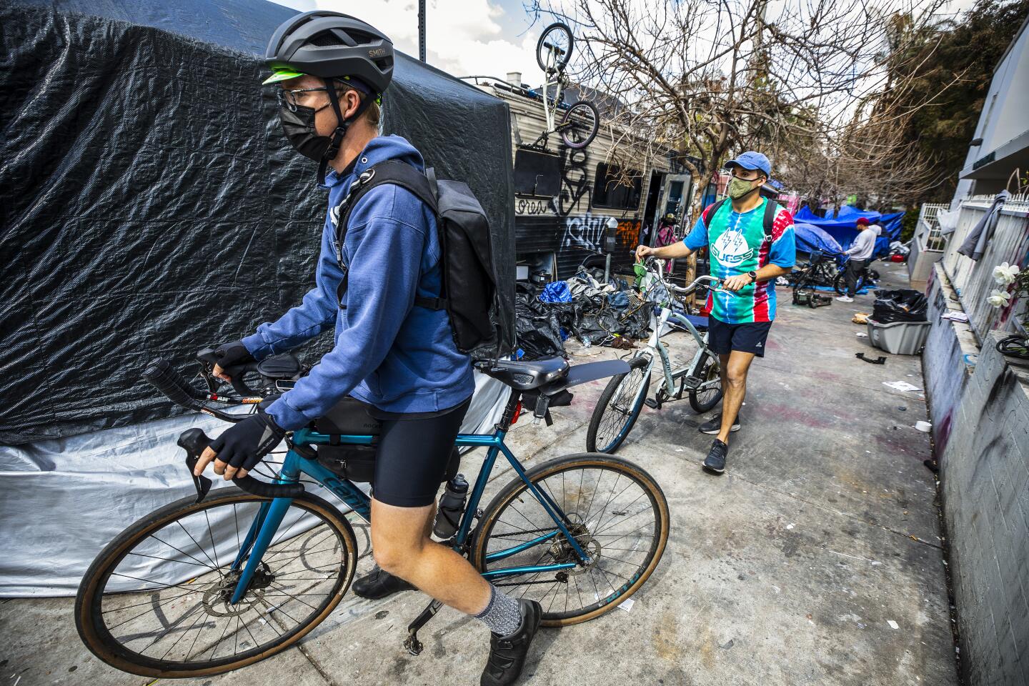 Bicycle Meals volunteers Kelly Wourms, left, and Max Banta leave a homeless encampment after delivering their last meals.