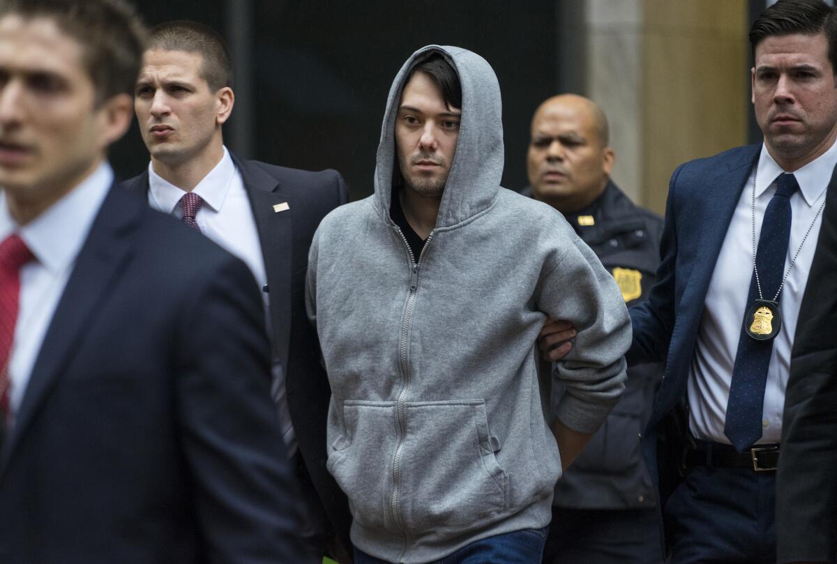 Martin Shkreli, the former hedge fund manager under fire for buying a pharmaceutical company and ratcheting up the price of a life-saving drug, is escorted Thursday by law enforcement agents in New York after being taken into custody following a securities probe.