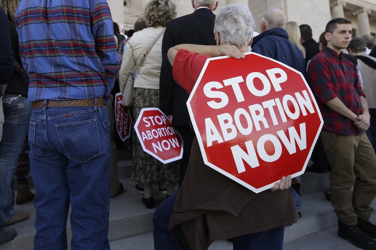 A woman carries an anti-abortion sign on her back during a rally in Little Rock, Ark., on Jan. 18. Arkansas is on the verge of further restricting the administration of abortion medication.