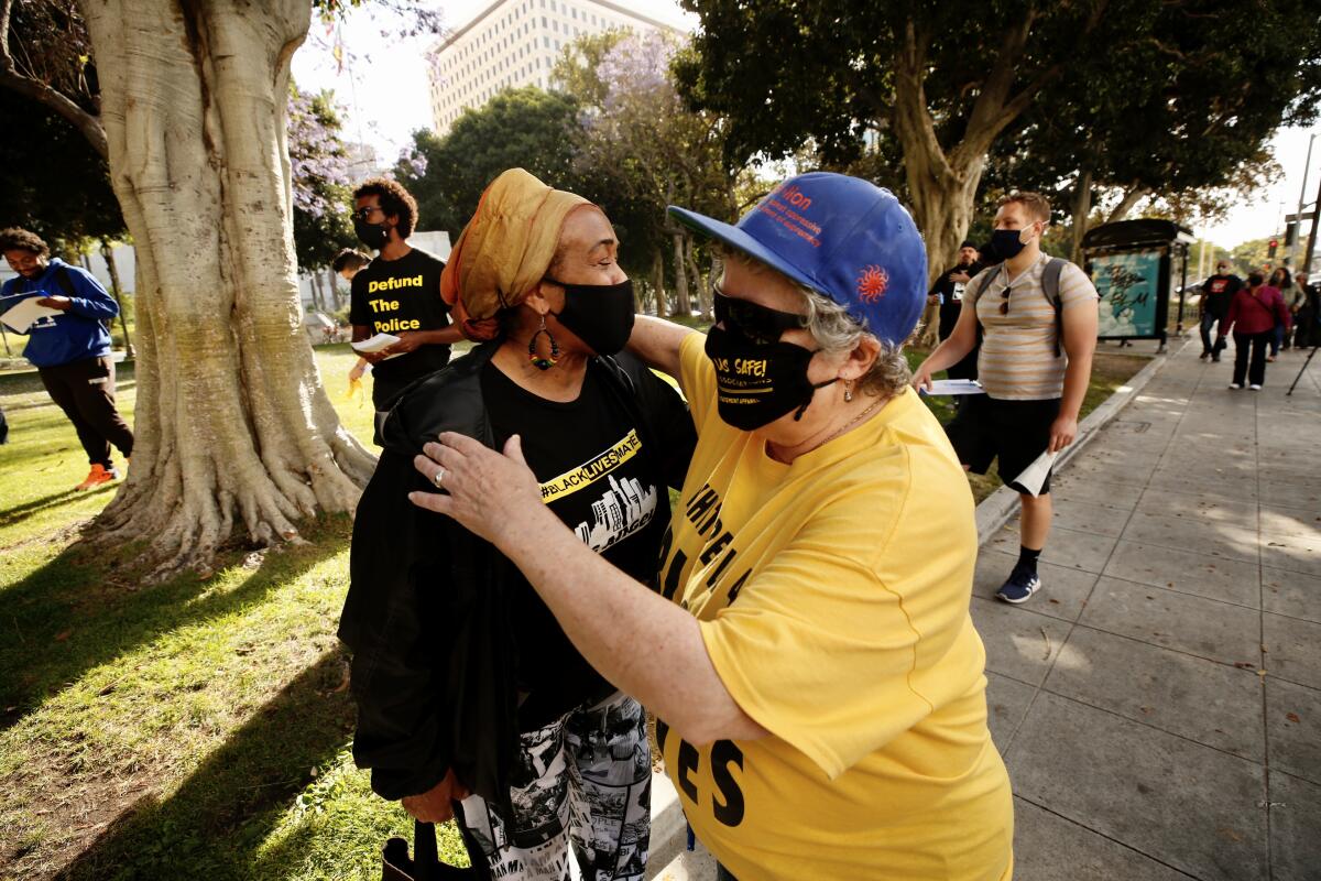 Audrey Georg, right, hugs Paula Minor before a rally outside L.A. City Hall