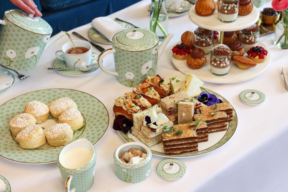 A spread of tea, sandwiches, pastries champagne, savory sandwiches, scones and sweet treats.