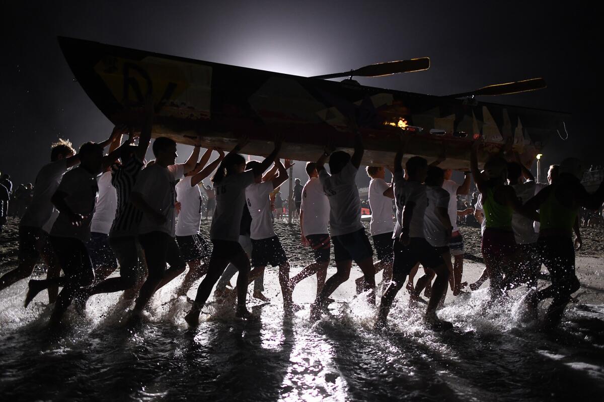 A team carries their two-person dory back to the beach.