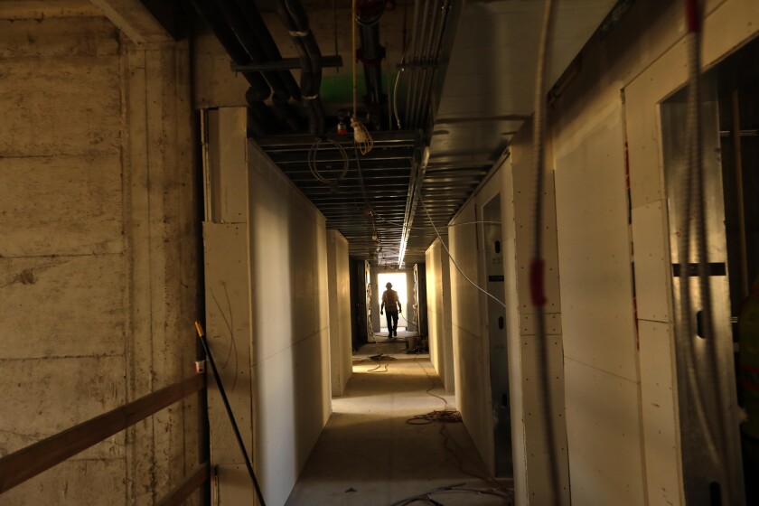 A construction worker walks down a hallway inside a building