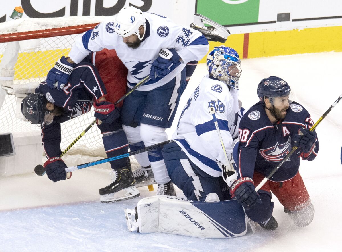 Columbus Blue Jackets left wing Nick Foligno, left, is dumped into the net by Tampa Bay Lightning defenceman Zach Bogosian (24) as Lightning goaltender Andrei Vasilevskiy (88) deals with Blue Jackets center Boone Jenner (38) during the first period of NHL Eastern Conference Stanley Cup first round playoff hockey action in Toronto, Monday, Aug. 17, 2020. (Frank Gunn/The Canadian Press via AP)
