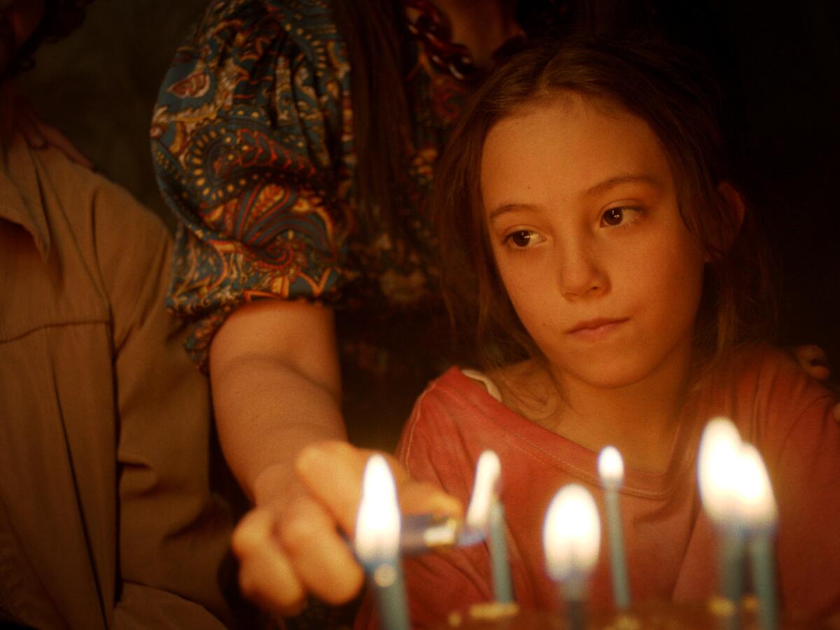 A young girl looks solemn as birthday candles are lit in "Tótem."