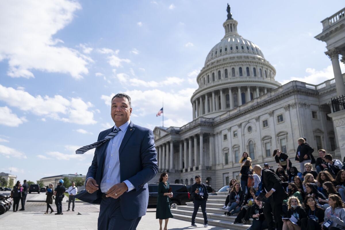 A man in a suit outside the Capitol next to a group of students