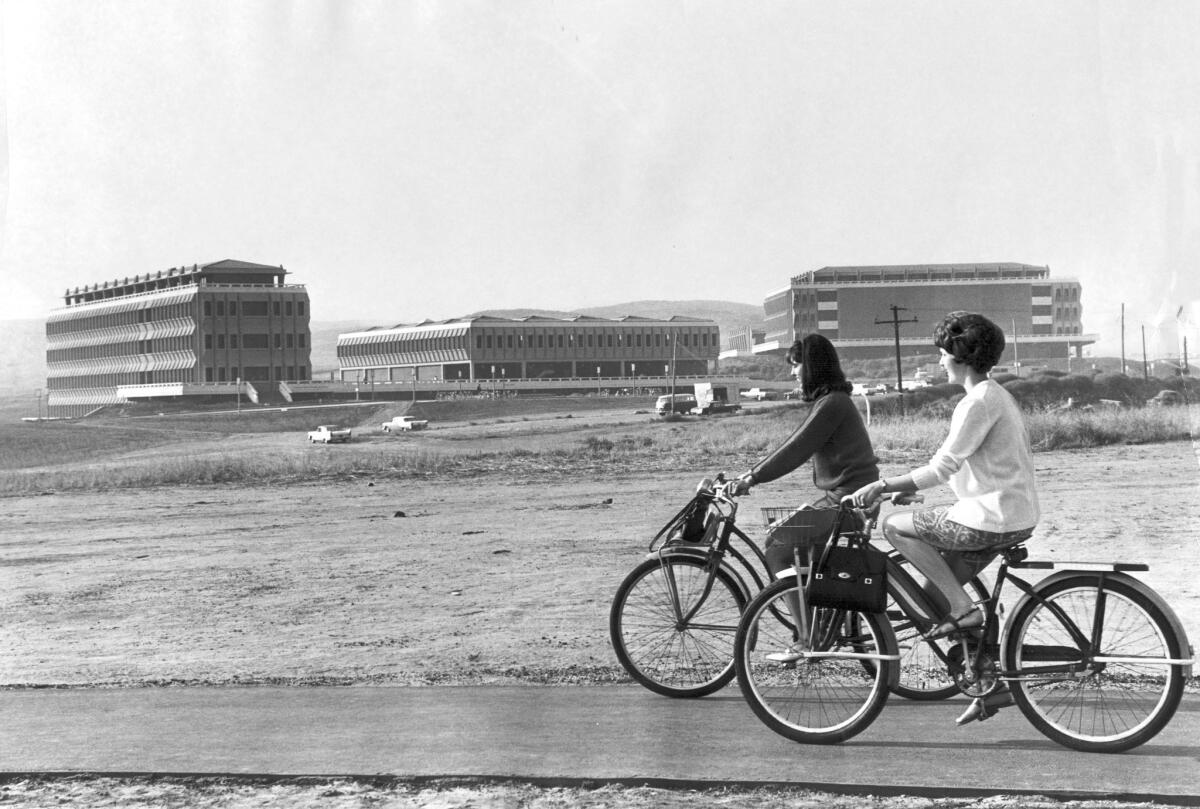 Barbara Terhune, right, and Linda Teply ride their bikes before attending opening-day classes at UC Irvine on Oct. 4, 1965.