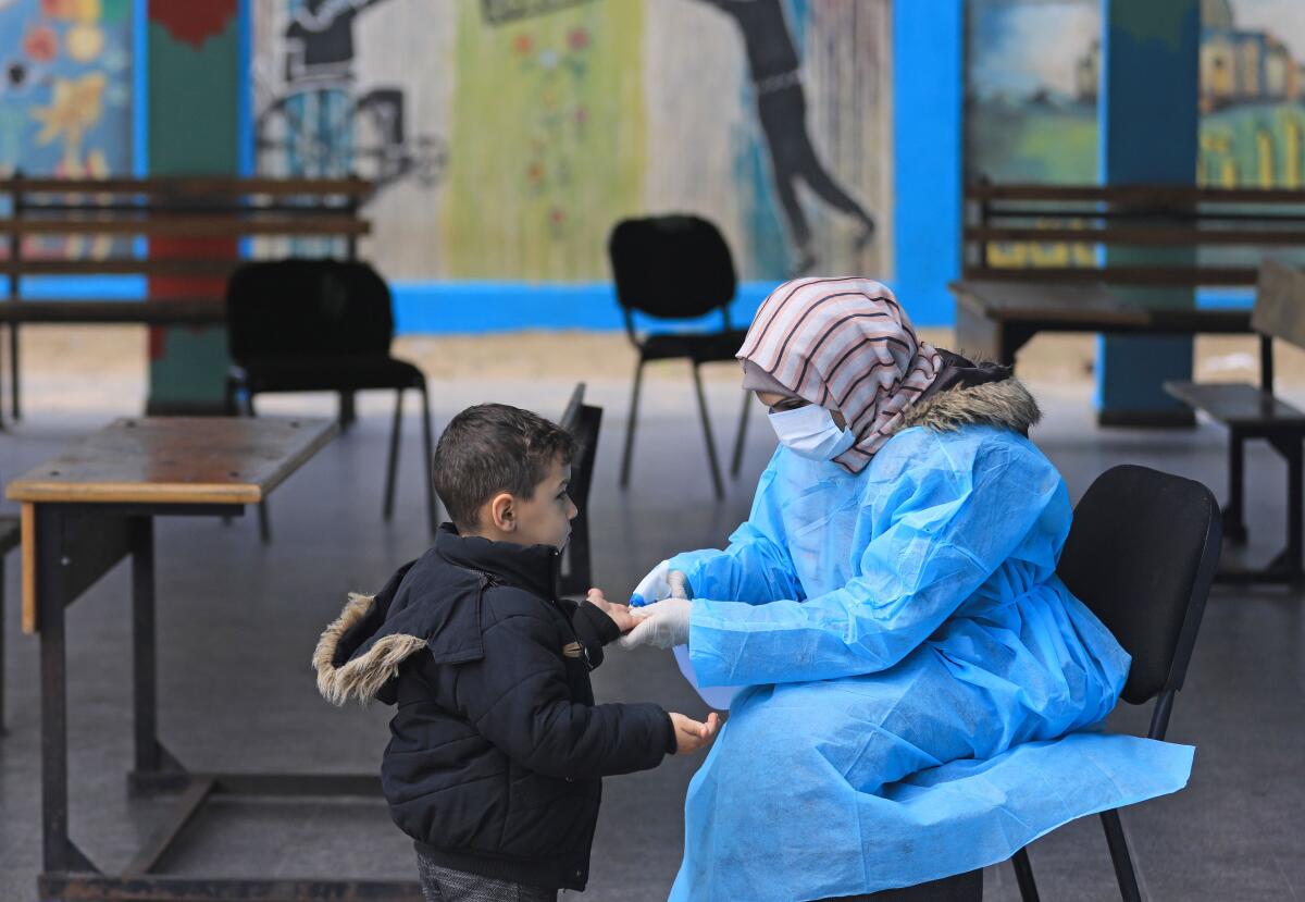 A Palestinian health worker wearing a protective mask checks the body temperature of a child at a United Nations Relief and Works Agency for Palestinian Refugees school in Gaza City.