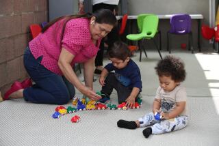 Lakewood, CA - May 17: Berta Amaya, left, assistant child care specialist, plays with Rey Reyes, center, 16-months-old in blue, and Luca Brown, 8 months old, at her daughter's Zoila Carolina Toma's family childcare center in Lakewood Wednesday, May 17, 2023. Zoila is licensed to care for up to 14 children from 8 months-12 years old Inside her center. They have a nap room, an art area, and a reading area to promote a comfortable atmosphere where students can engage in their activities. Currently, Zoila is at capacity, but she is constantly receiving calls from families looking for high-quality care. The need for care is desperately there, but there are not enough family child care centers to cover the needs of families, and few want to enter an industry where wages are so low. (Allen J. Schaben / Los Angeles Times)