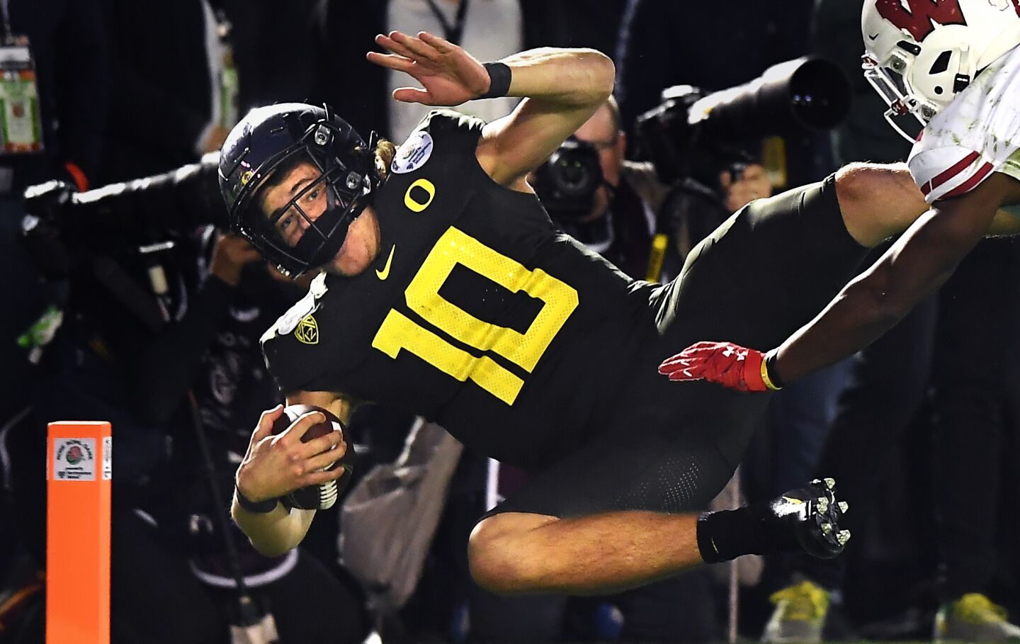 Oregon quarterback Justin Herbert scores the go-ahead touchdown in front of Wisconsin cornerback Faion Hicks during the fourth quarter.