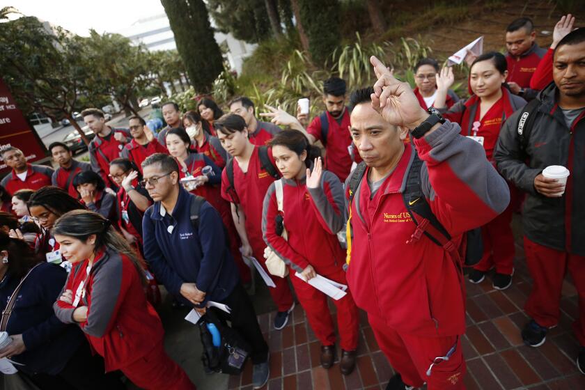 LOS ANGELES, CA - MARCH 10, 2020 Registered nurses Carl Bicera and Marichelle Villamil, right to left, join healthcare workers at Keck Hospital of USC near downtown Los Angeles gathered in front of the hospital before their shifts early Wednesday morning to listen to representatives of the California Nurses Association which is mad about the lack of preparation for COVID-19 outbreaks. The nurses union will be holding actions at universities around the state. (Al Seib / Los Angeles Times)