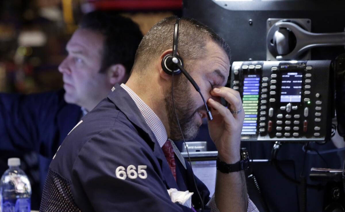 Trader Kevin Lodewick on the floor of the New York Stock Exchange where stocks fell sharply before recovering somewhat following discouraging news on the U.S. economy and a weaker forecast of global growth.