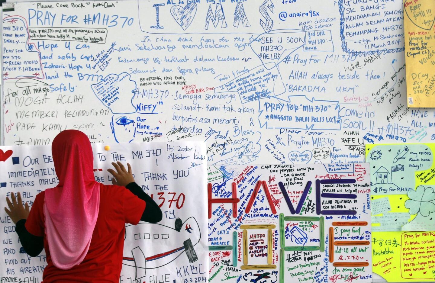 A well-wisher hangs up messages for the passengers of the missing Malaysian Airline plane at Kuala Lumpur International Airport, Malaysia, 14 March 2014.