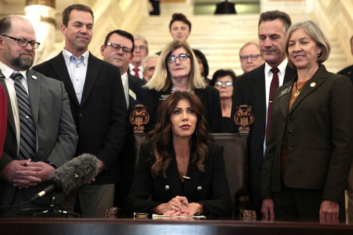 South Dakota Gov. Kristi Noem signs a bill Thursday, Feb. 3, 2022, at the state Capitol in Pierre, S.D., that will ban transgender women and girls from playing in school sports leagues that match their gender identity. (AP Photo/Stephen Groves)
