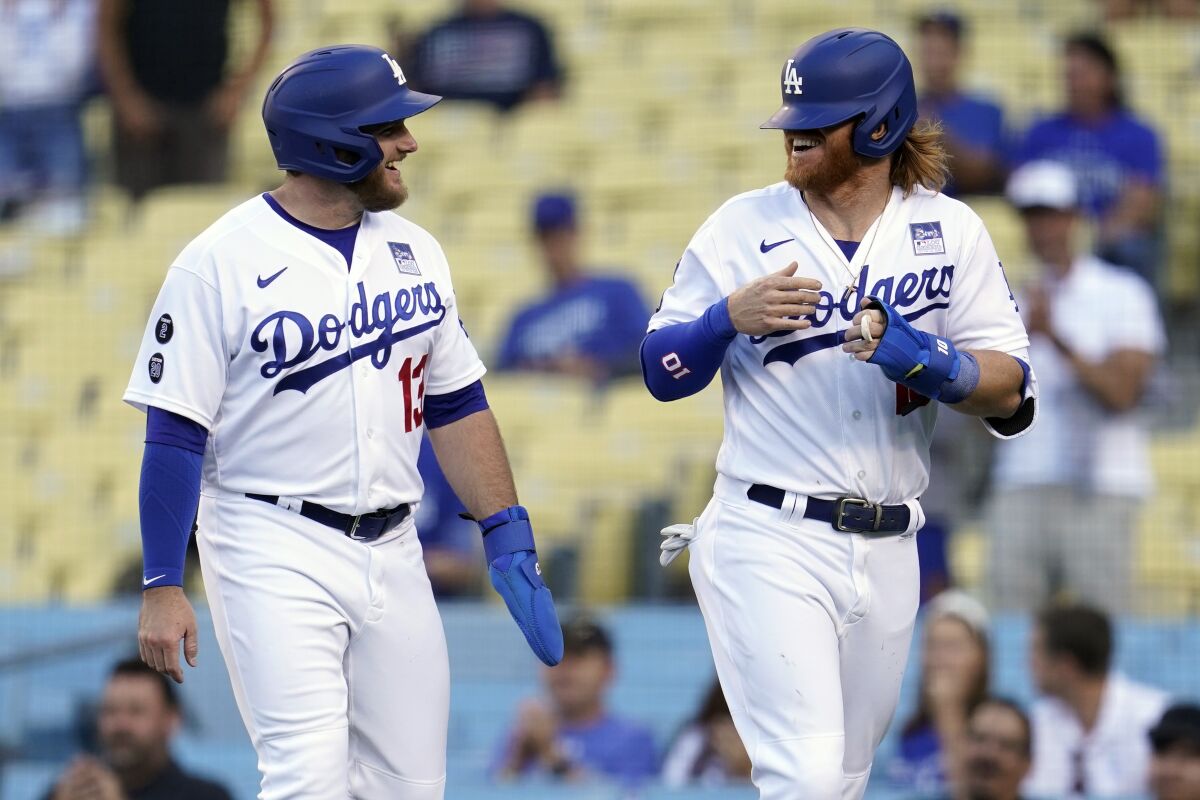 The Dodgers' Justin Turner smiles with his helmet over his eyes and laughs with Max Muncy 
