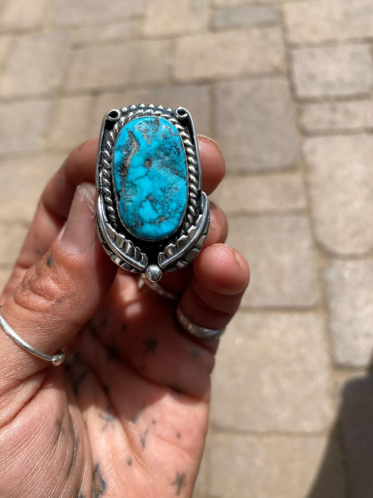 picture of a hand holding a silver and turquoise ring