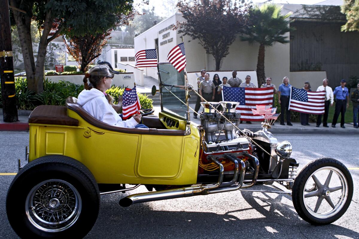 As officers waved from the sidewalk, members of the Early Rodders Car Club drove past the Los Angeles County Crescenta Valley Sheriff Station to honor heroes and victims of 9/11 in La Crescenta on Wednesday, Sept. 11, 2013. About 25 cars drove past local fire stations as well waving USA flags.