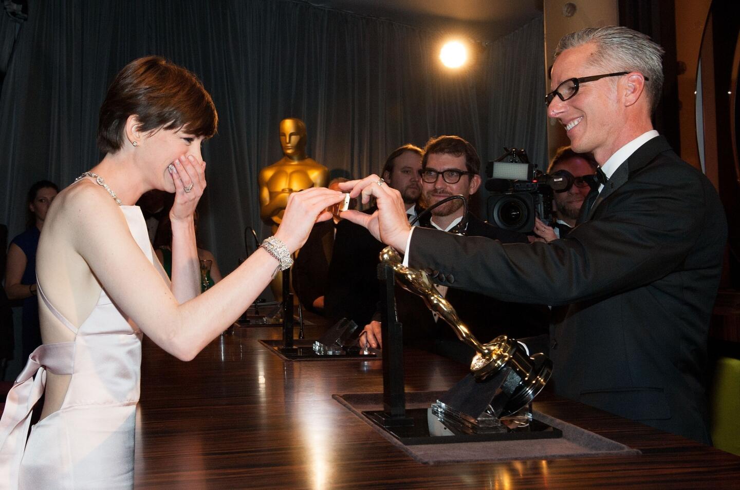 Supporting actress winner Anne Hathaway gets emotional while looking at her name on the engraved plate of her Oscar statue.