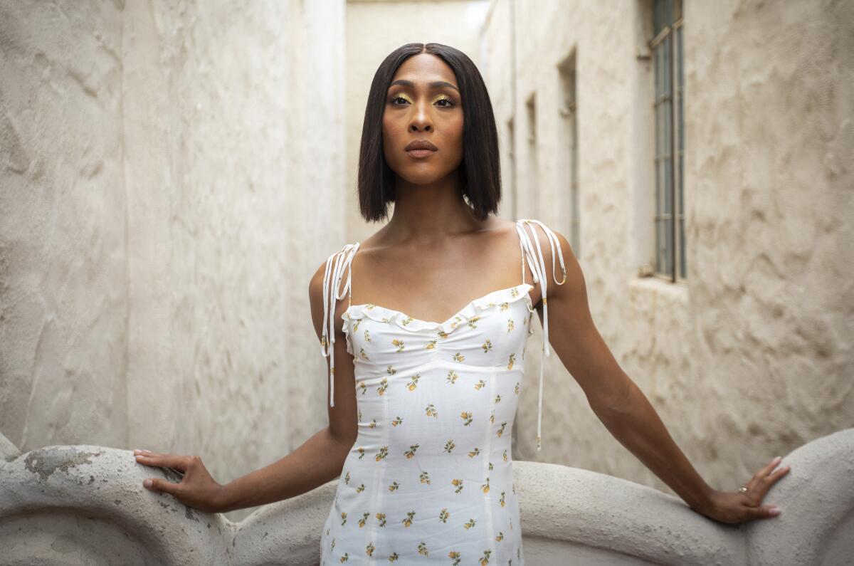 A woman with short, straight hair posing in a white dress