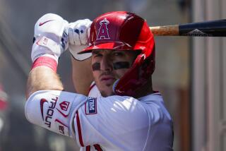 Los Angeles Angels designated hitter Mike Trout warms up in the dugout during a baseball game.