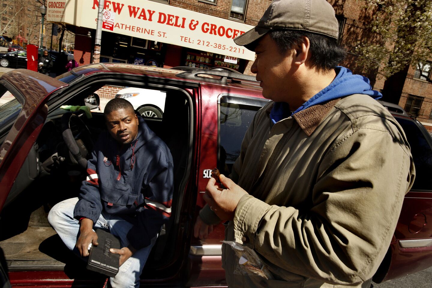 Kenneth Eng offers Joel Mangal, left, adviceabout his car's muffleron the edge of New York's Chinatown.