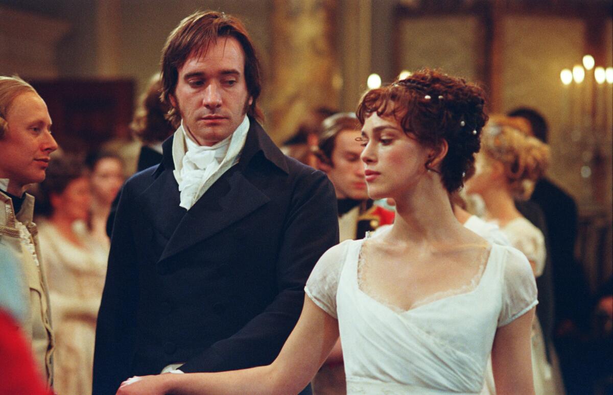 A man and a woman in formal attire dance at a ball in 19th century England.