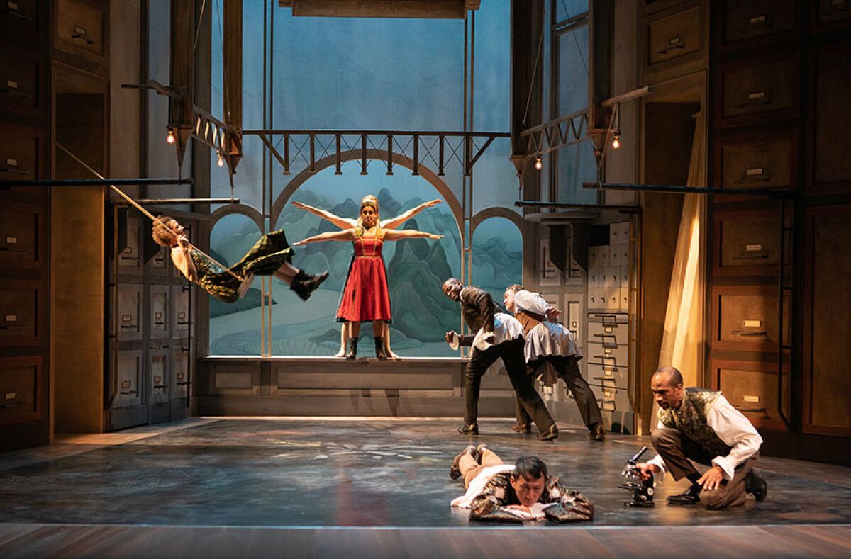 Actors inhabit a world that looks like a giant apothecary desk.