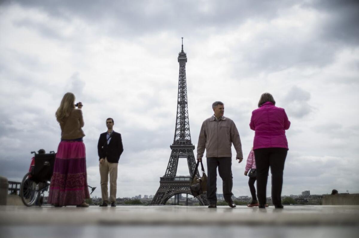 Tourists take pictures near the Eiffel Tower in Paris earlier this month.