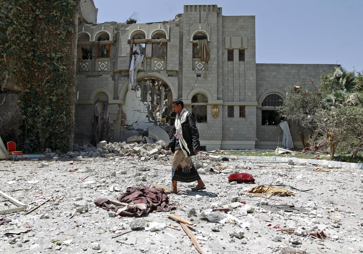 A gunman loyal to former Yemeni President Ali Abdullah Saleh walks amid the wreckage of Saleh's residence following airstrikes Sunday.