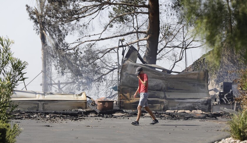 The son of the homeowner in Alpine walks past what was the front of the family home on Olive View Road. The West fire was the largest of several brush fires that broke out during a record-breaking heat wave in Southern California.