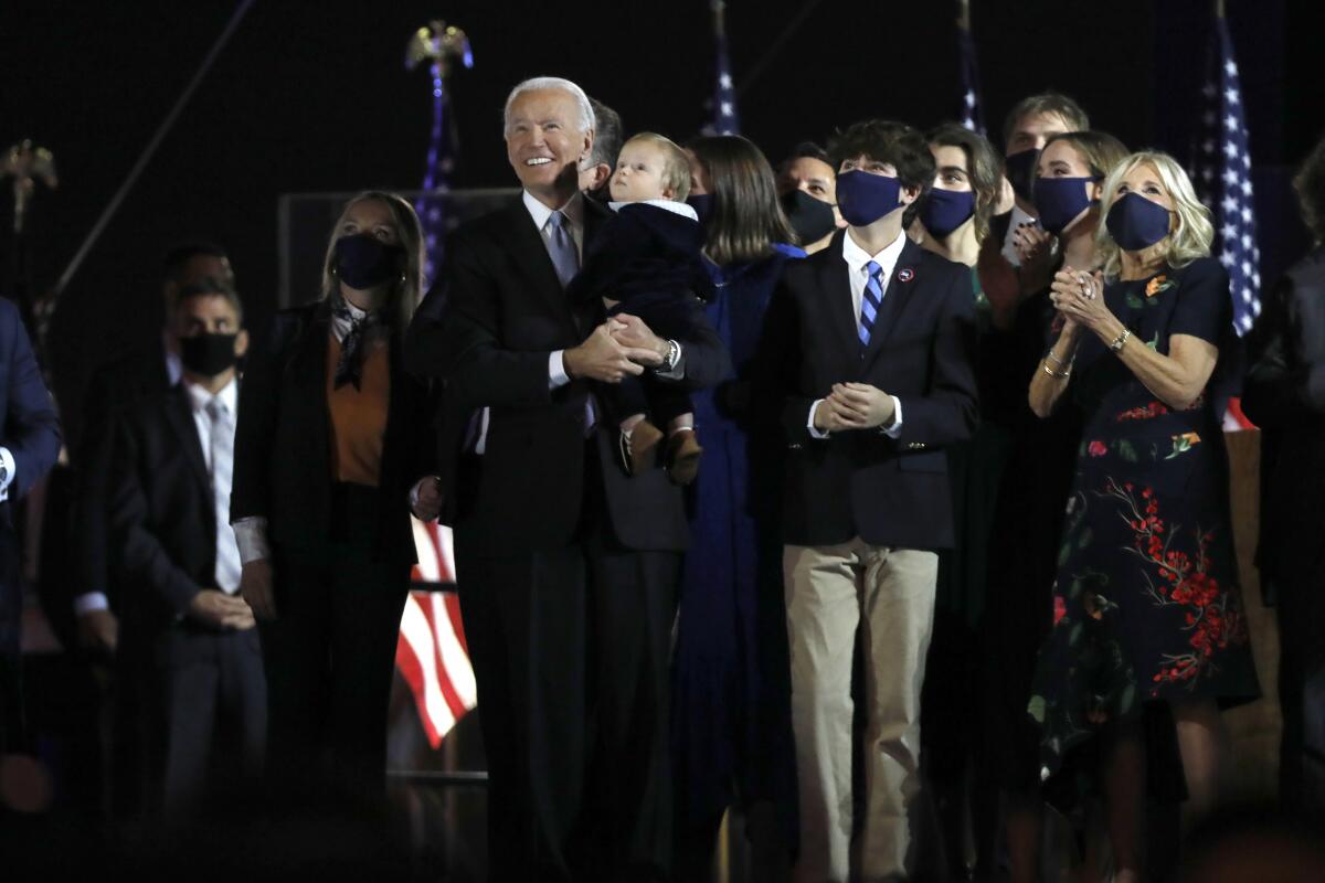 President-elect Joe Biden holds his grandchild watching fireworks after his rally after defeating Donald Trump.