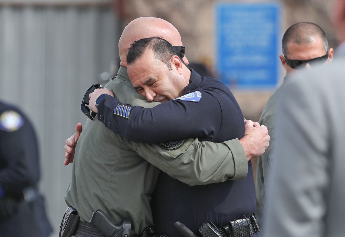 Lt. Jim Cota, right, of the Laguna Beach police, hugs a member of the Huntington Beach Helicopter Unit.