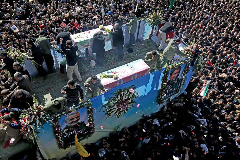 Mourners gather around a vehicle carrying the coffin of slain Iranian Gen. Qasem Soleimani in his hometown of Kerman on Tuesday.