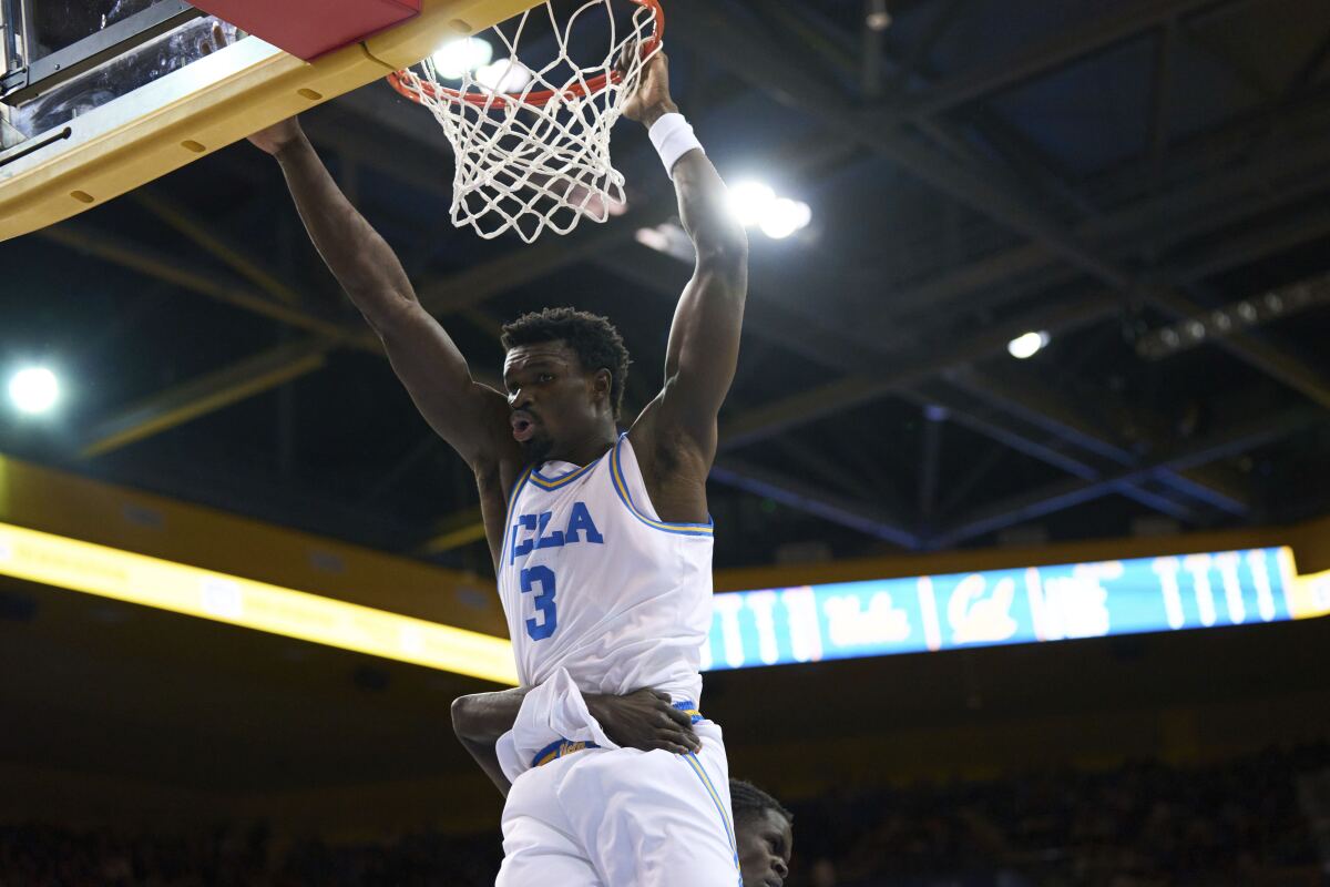 UCLA forward Adem Bona hangs from the rim after a dunk against California on Saturday.
