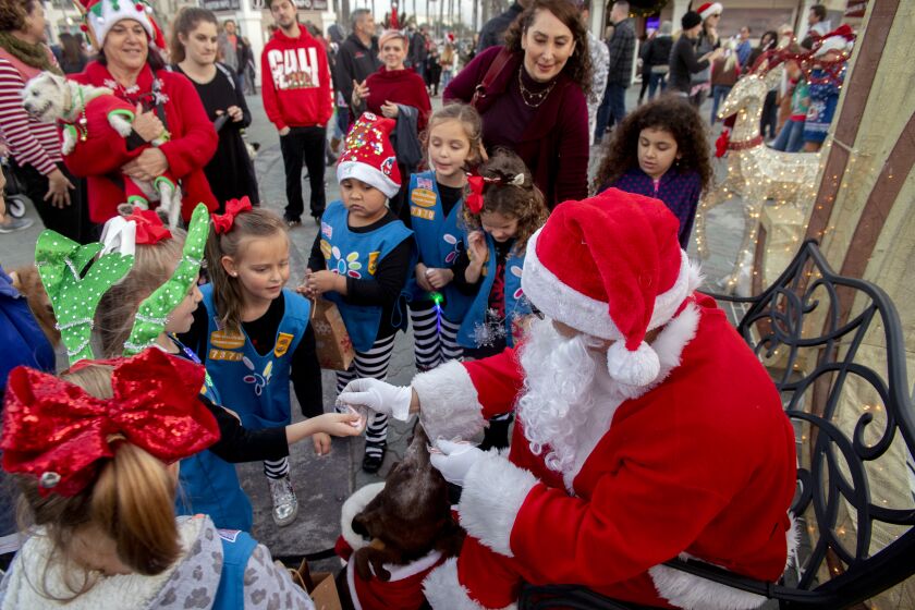 Accompanied by his dog Miles, Santa (Dave Basok) distributes holiday candy canes. (Photo by Spencer Grant)