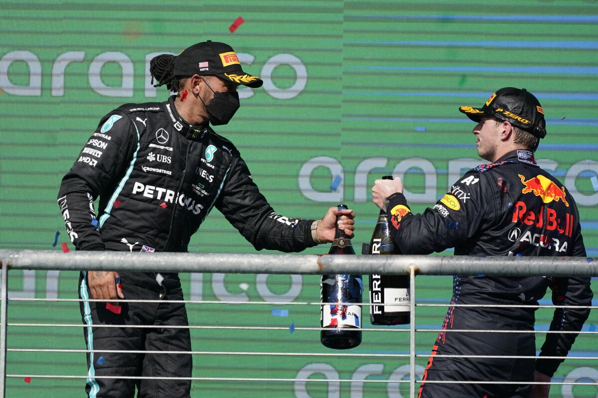 Red Bull driver Max Verstappen, of the Netherlands, and Mercedes driver Lewis Hamilton, of Britain, bump bottles following the Formula One U.S. Grand Prix auto race at the Circuit of the Americas, Sunday, Oct. 24, 2021, in Austin, Texas. Verstappen won the race and Hamilton finished second. (AP Photo/Darron Cummings)