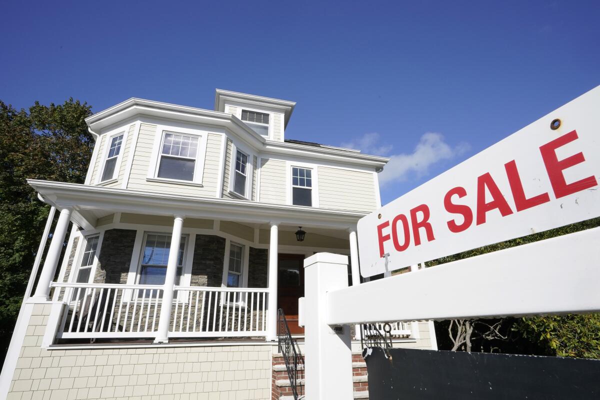 A for sale sign stands in front of a house