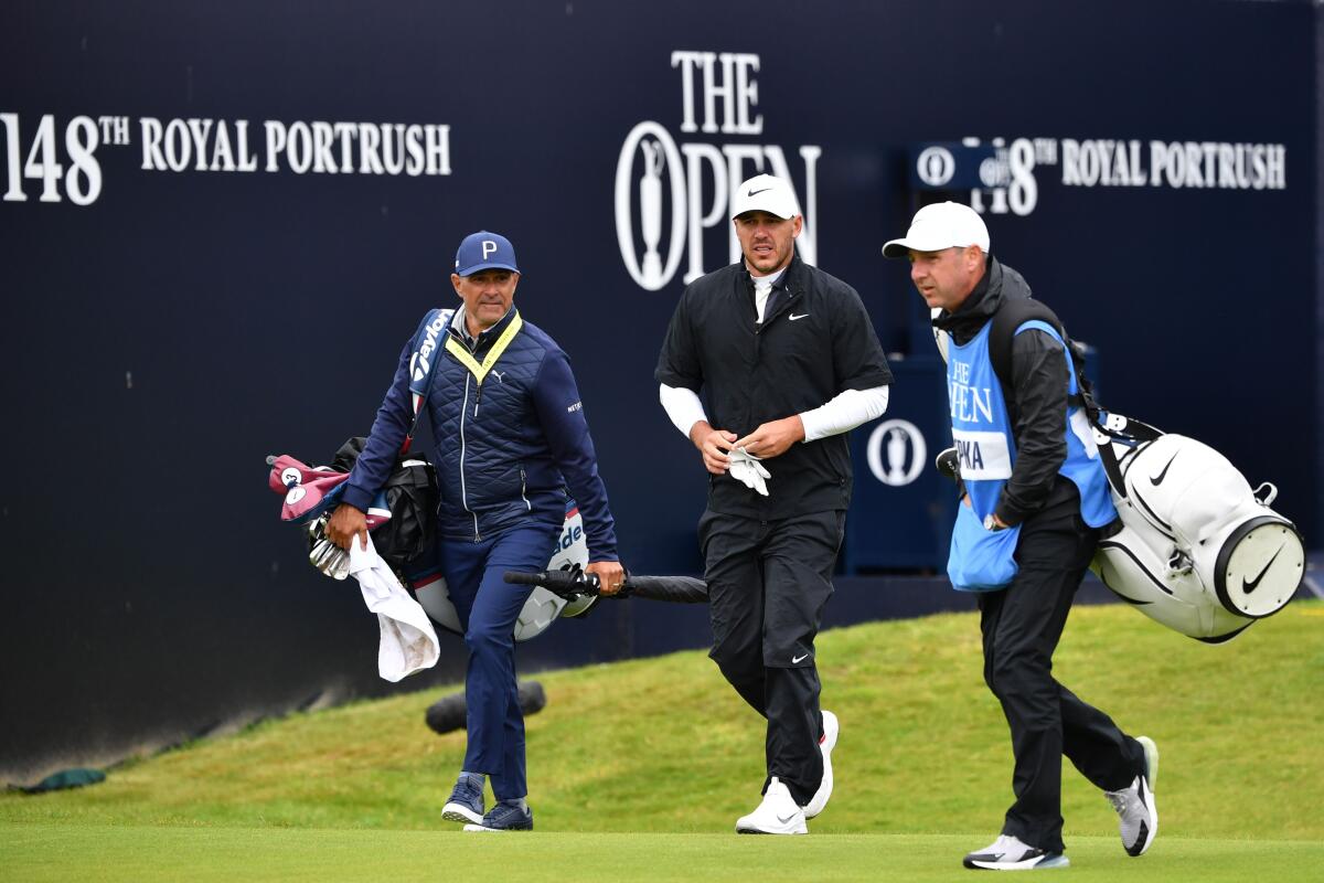 Brooks Koepka, center, and caddie Ricky Elliott, right, head down a fairway during a practice round at Portrush Golf Club on July 17, 2019.