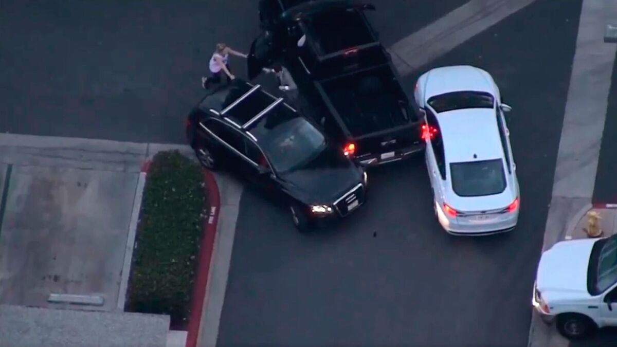 In this screen grab from video provided by KNBC-TV, an SUV is carjacked from the motorist, left, and nearly pins a good Samaritan, right, between vehicles during a high-speed chase in Irvine on Monday.