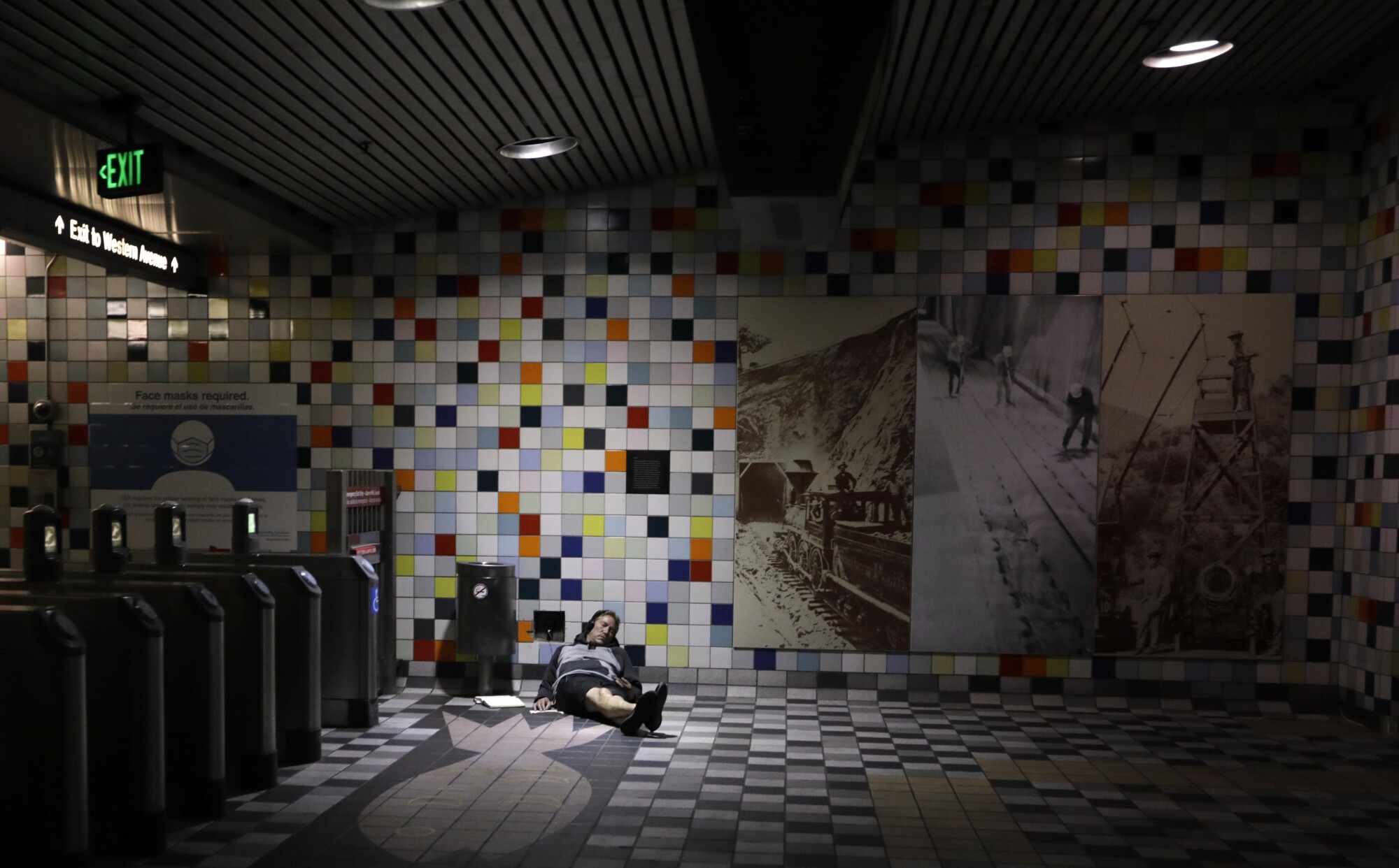 A man napping with his head against the wall of the train station